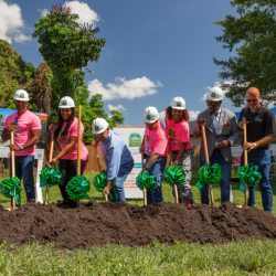 People digging shovels into dirt for groundbreaking 
